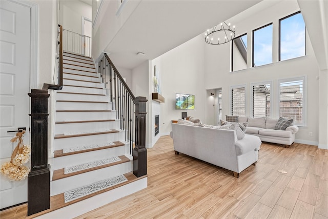 living room featuring a high ceiling, a chandelier, and light wood-type flooring