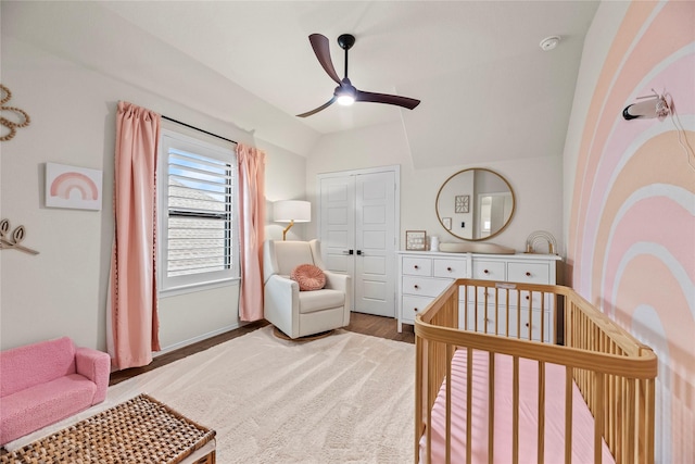 bedroom with hardwood / wood-style flooring, a closet, vaulted ceiling, ceiling fan, and a nursery area