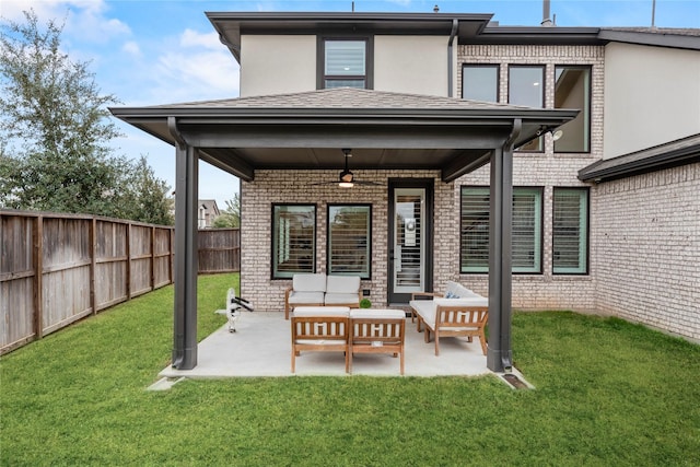 rear view of house featuring ceiling fan, an outdoor living space, a patio, and a yard