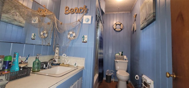 bathroom with vanity, wood walls, radiator, crown molding, and toilet