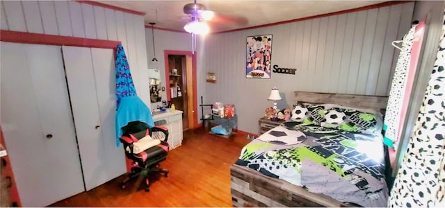 bedroom with crown molding, ceiling fan, a closet, and wood-type flooring