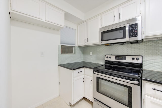 kitchen featuring light tile patterned floors, backsplash, stainless steel appliances, and white cabinetry