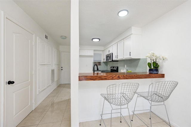 kitchen featuring sink, stainless steel appliances, backsplash, kitchen peninsula, and a kitchen bar