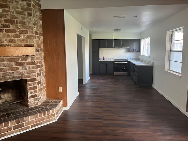 kitchen with gray cabinetry, sink, a brick fireplace, dark hardwood / wood-style flooring, and stainless steel stove