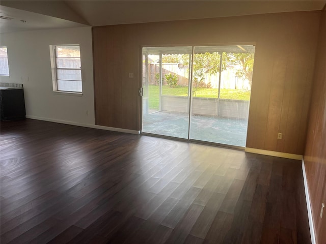 spare room featuring dark wood-type flooring and wooden walls