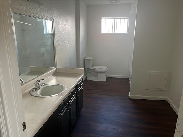 bathroom with vanity, toilet, wood-type flooring, and a tile shower