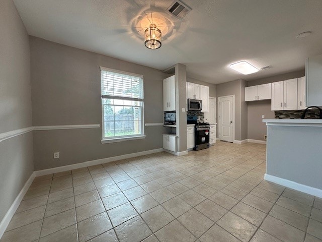 kitchen featuring sink, stainless steel appliances, light tile patterned floors, backsplash, and white cabinets