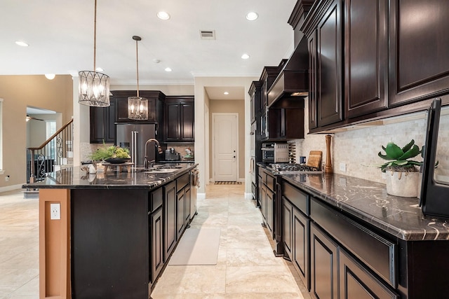 kitchen with decorative light fixtures, sink, a kitchen island with sink, and tasteful backsplash