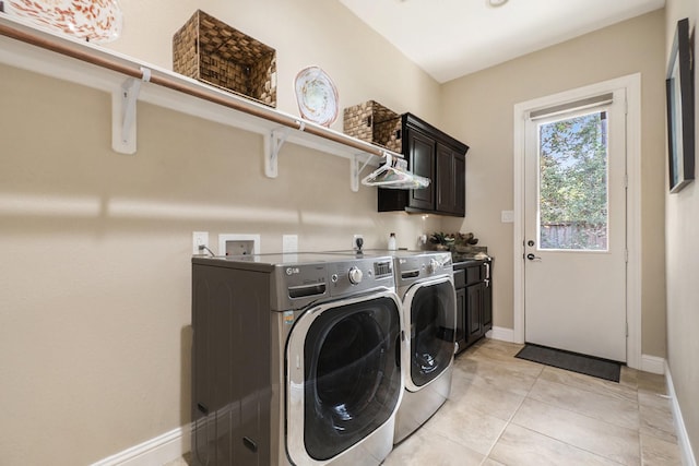 clothes washing area featuring light tile patterned flooring, cabinets, and washing machine and dryer