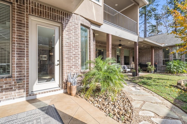 entrance to property with a patio area, ceiling fan, and a balcony