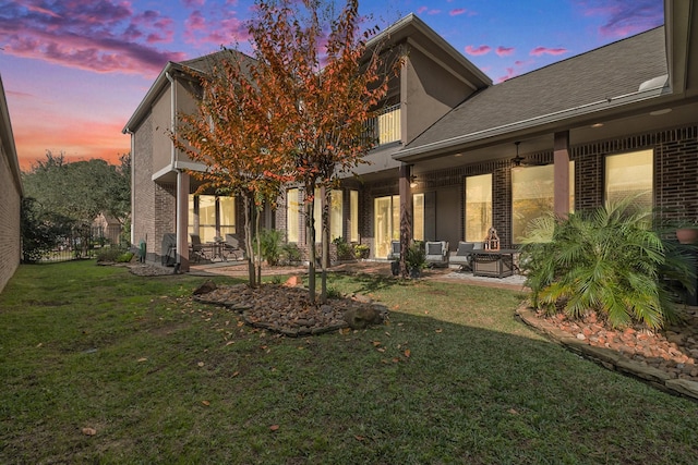 back house at dusk with a patio area and a yard