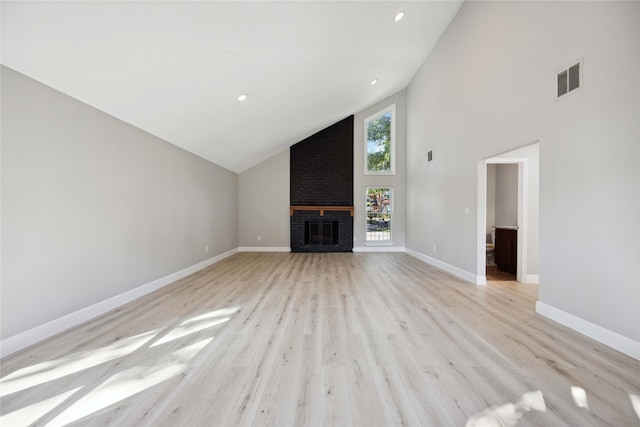 unfurnished living room featuring light wood-type flooring, high vaulted ceiling, and a brick fireplace