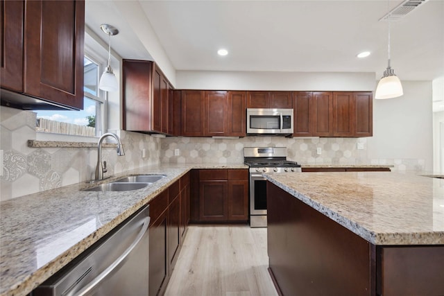 kitchen featuring light stone countertops, light wood-type flooring, sink, and appliances with stainless steel finishes