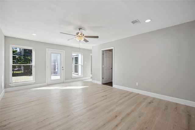 empty room featuring ceiling fan, a wealth of natural light, and light hardwood / wood-style flooring