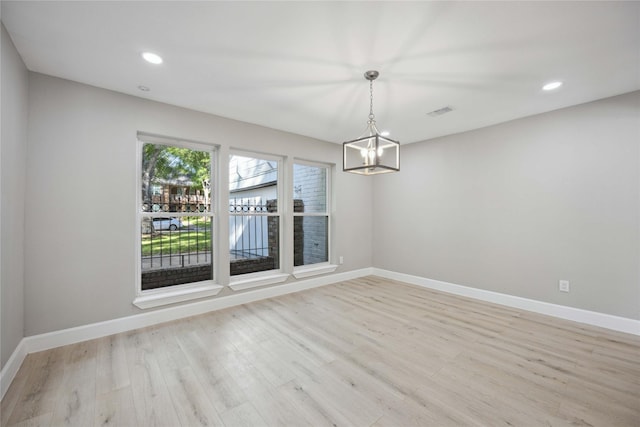 unfurnished dining area featuring light hardwood / wood-style floors and an inviting chandelier