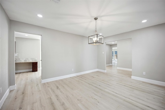 unfurnished dining area featuring light hardwood / wood-style flooring and a notable chandelier