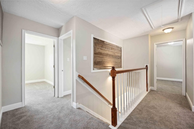 hallway with a textured ceiling and light colored carpet