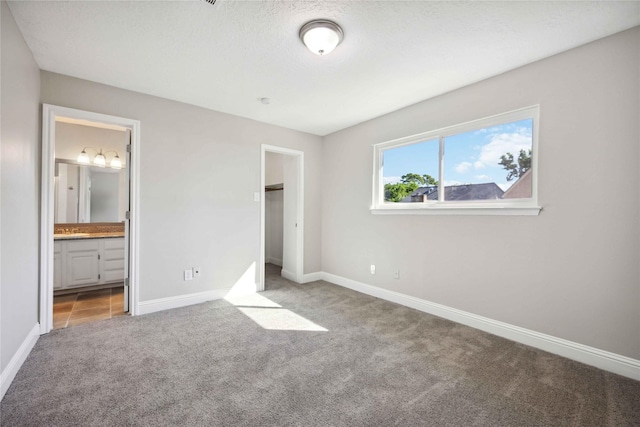 unfurnished bedroom featuring carpet flooring, sink, a textured ceiling, and connected bathroom