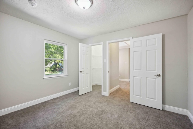 unfurnished bedroom featuring carpet flooring, a textured ceiling, and a closet