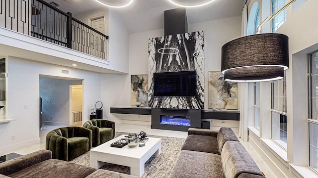 living room featuring a fireplace, a high ceiling, and a healthy amount of sunlight