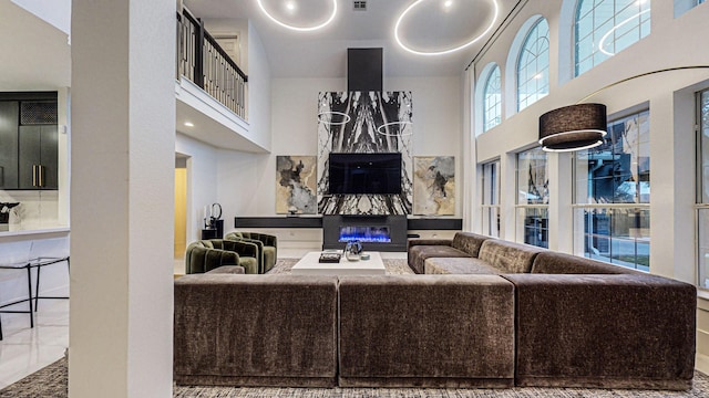 living room with a high end fireplace and a towering ceiling