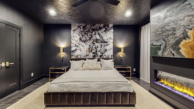 bedroom featuring a large fireplace and ceiling fan