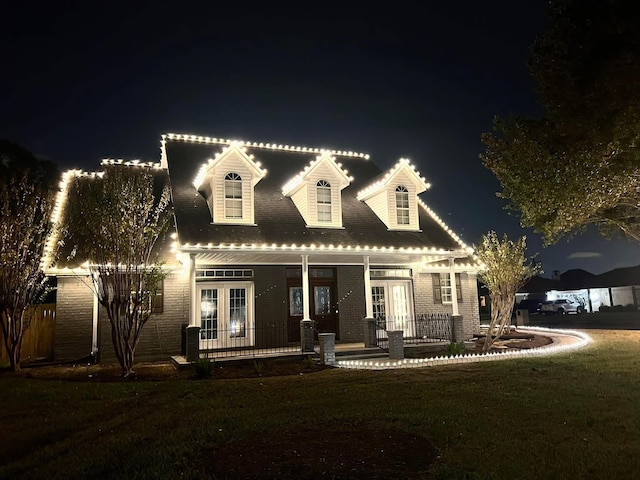 cape cod house featuring french doors, a yard, and a porch