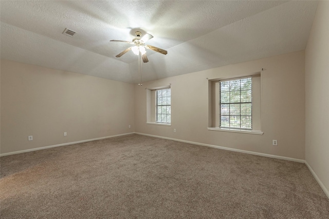 empty room featuring carpet, a textured ceiling, vaulted ceiling, and ceiling fan