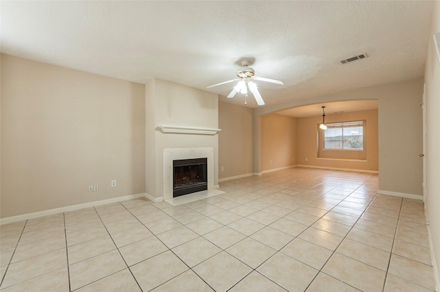 unfurnished living room featuring ceiling fan, light tile patterned flooring, and a textured ceiling