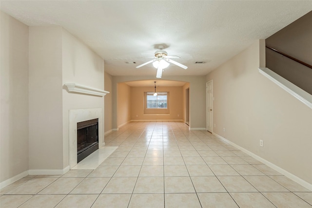 unfurnished living room featuring ceiling fan, light tile patterned flooring, and a textured ceiling