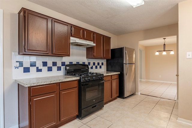 kitchen with black gas range, stainless steel refrigerator, tasteful backsplash, decorative light fixtures, and light tile patterned floors