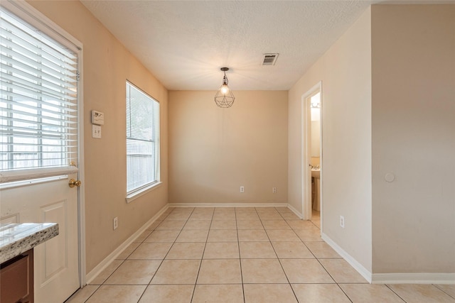 unfurnished dining area with light tile patterned floors and a textured ceiling