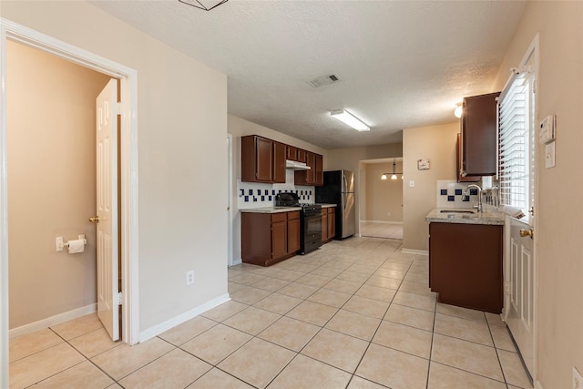 kitchen with black gas stove, tasteful backsplash, light tile patterned floors, and sink