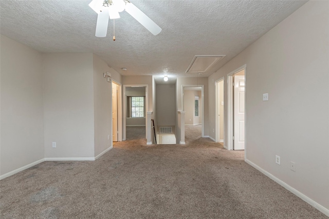 spare room featuring a textured ceiling, light colored carpet, and ceiling fan