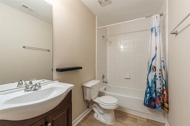 full bathroom with shower / bath combination with curtain, wood-type flooring, a textured ceiling, toilet, and vanity