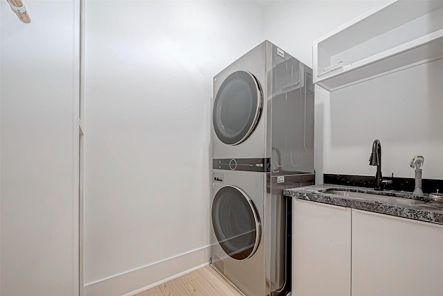 laundry area with stacked washer / dryer, sink, and light hardwood / wood-style floors