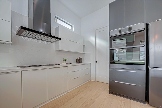 kitchen featuring white cabinetry, light hardwood / wood-style flooring, wall chimney exhaust hood, and stainless steel appliances