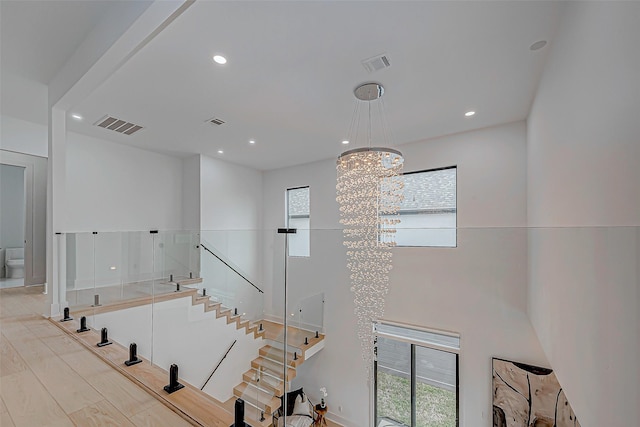 stairs with hardwood / wood-style floors, a healthy amount of sunlight, and an inviting chandelier