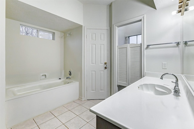 bathroom featuring tile patterned floors, a bathtub, vanity, and a textured ceiling