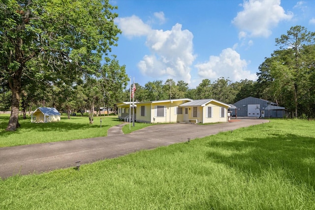 single story home featuring a front lawn and an outdoor structure