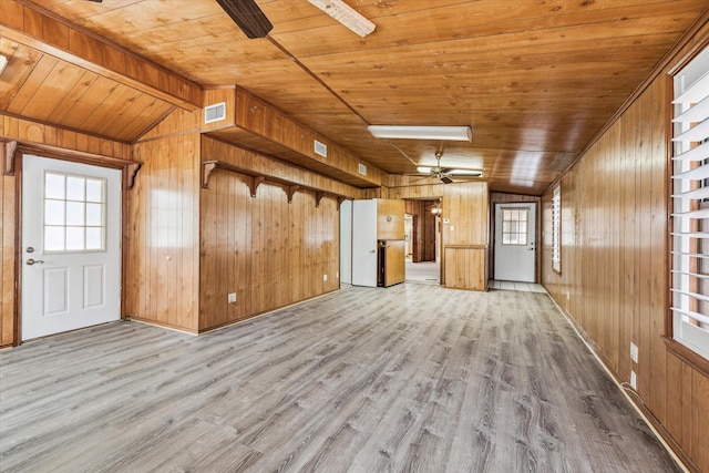 unfurnished living room with wood ceiling, wood walls, lofted ceiling with beams, and light wood-type flooring