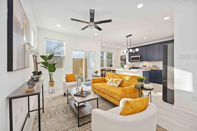 living room with light hardwood / wood-style flooring and ceiling fan with notable chandelier