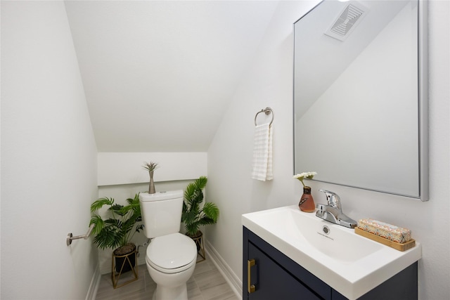 bathroom featuring vanity, vaulted ceiling, and toilet