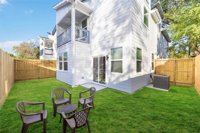 rear view of property featuring a yard, central AC, and a balcony