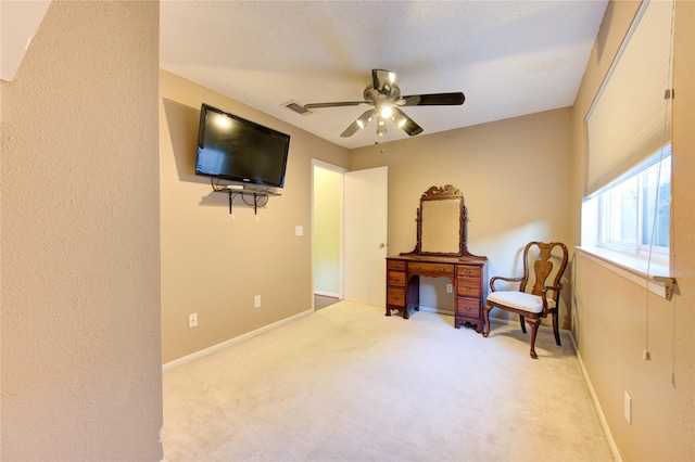 sitting room with ceiling fan, light colored carpet, and a textured ceiling