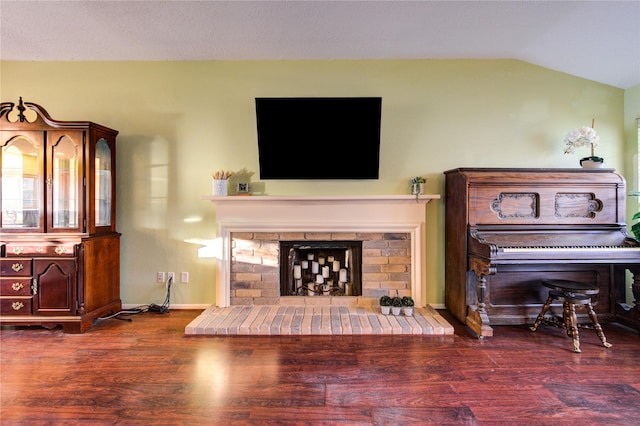 living room featuring dark hardwood / wood-style floors, lofted ceiling, and a fireplace