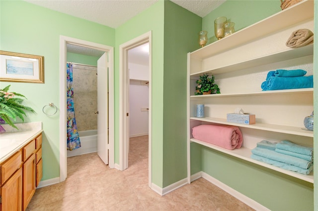 interior space with vanity, shower / bathtub combination with curtain, and a textured ceiling