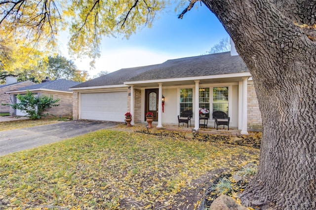 ranch-style house featuring a garage, covered porch, and a front lawn