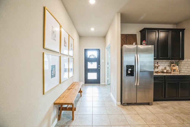 kitchen with light stone countertops, stainless steel fridge with ice dispenser, tasteful backsplash, and light tile patterned floors