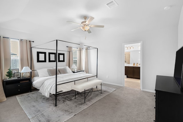 bedroom featuring ceiling fan, light colored carpet, and connected bathroom